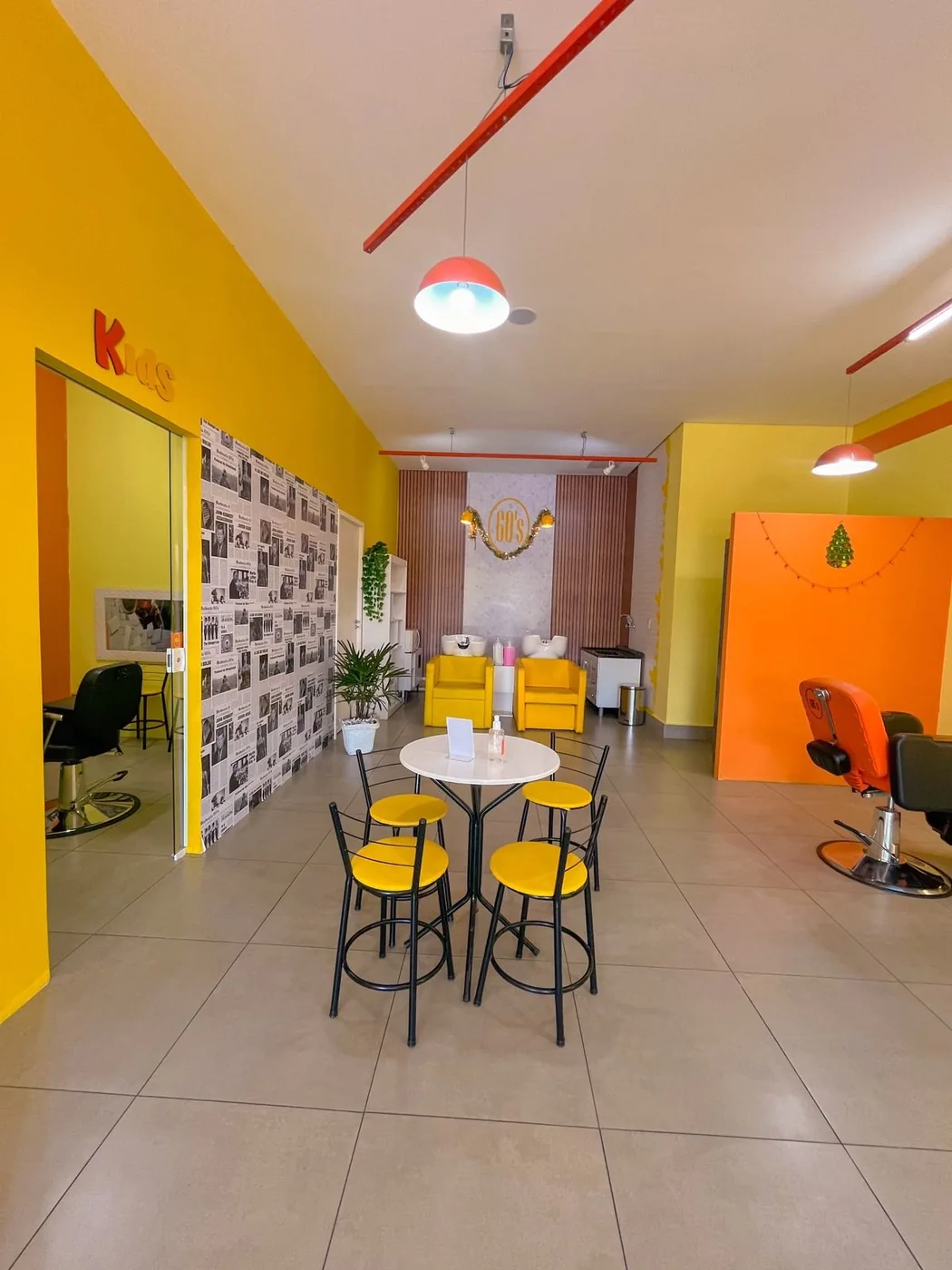 Área de espera da Barbearia 60's com mesas e banquetas amarelas